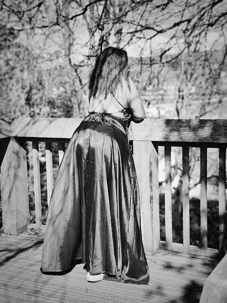 Black and white photo of Lucinda leaning against a fence in a backless dress